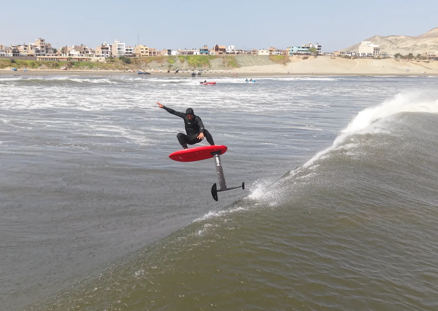 Fernando Mizo riding a red foil board above a breaking wave.