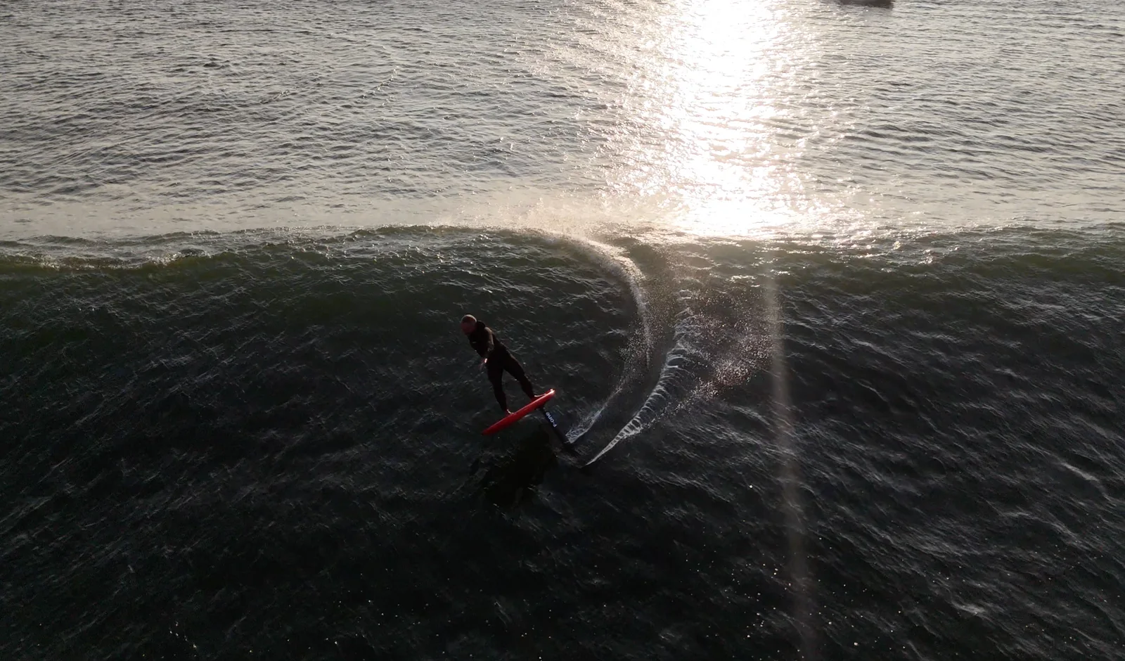 Fernando Mizo foiling through a sunlit ocean swell.