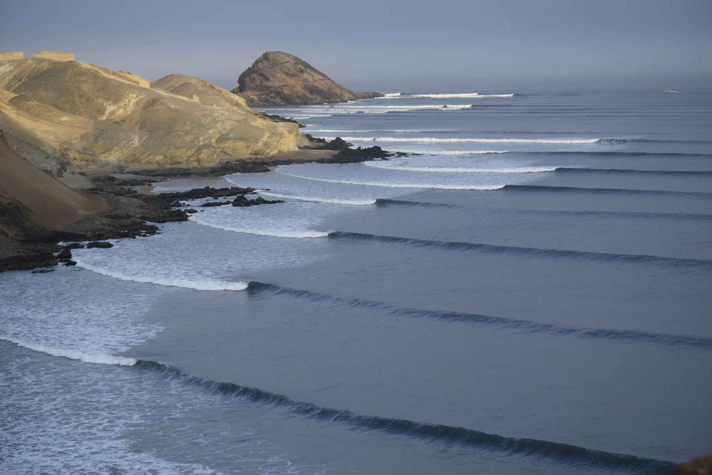 Long parallel waves peeling along the rocky point at Chicama, Peru.