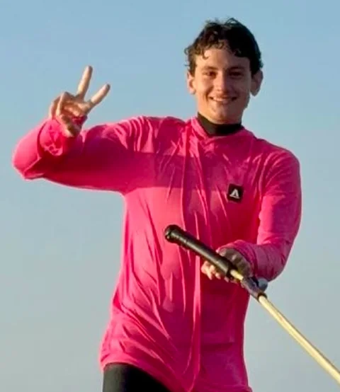 Marcelo Orsini smiling in a pink rash guard while holding a tow handle.