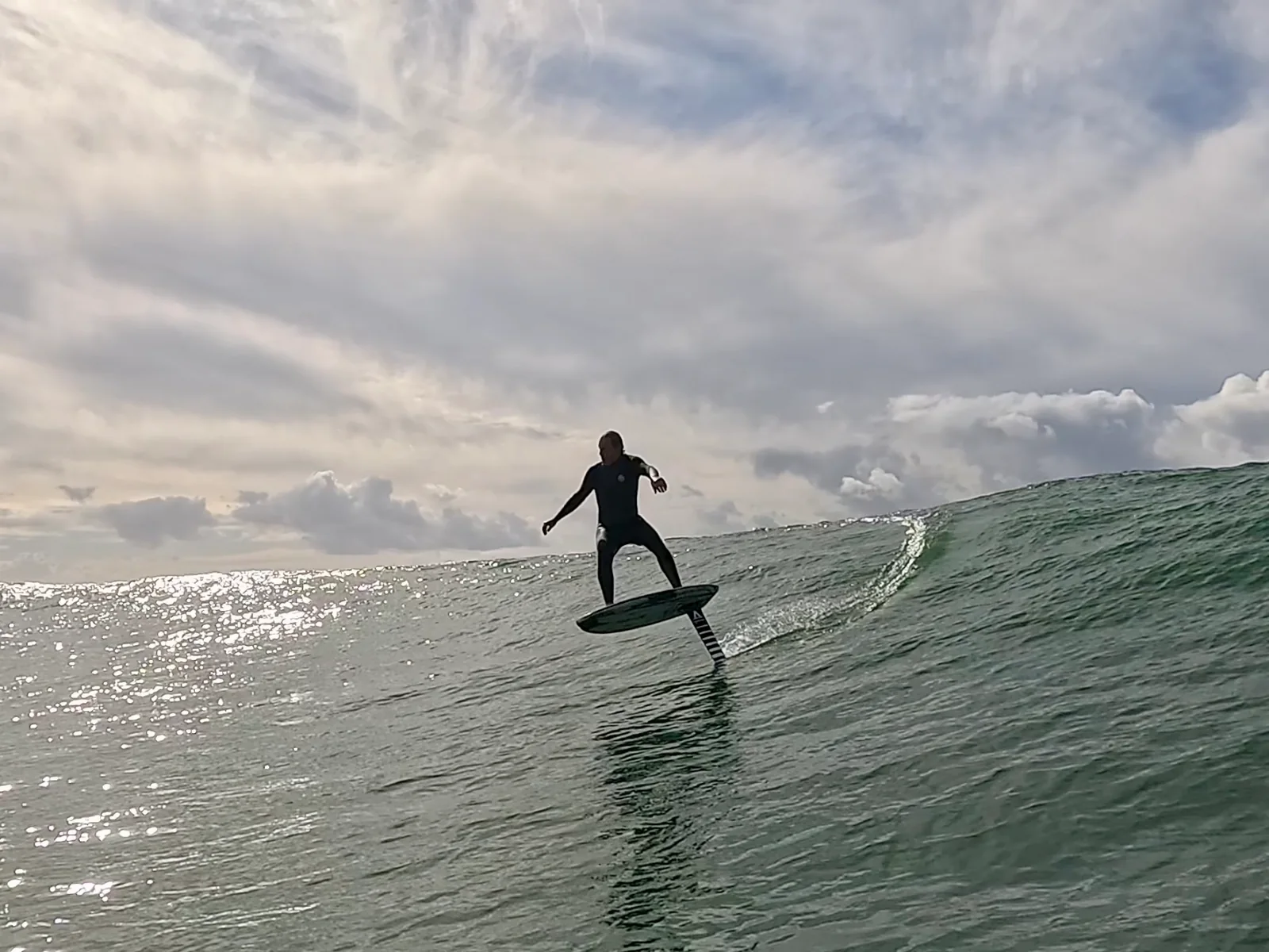 Ted Robinson foil surfing across the face of an ocean wave.